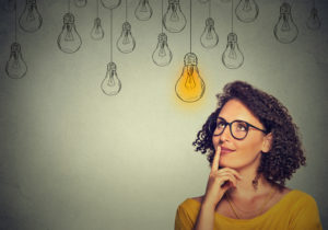 woman in glasses looking up with light idea bulb